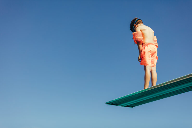 Low Angle Shot Of Boy With Sleeves Floats On Diving Board