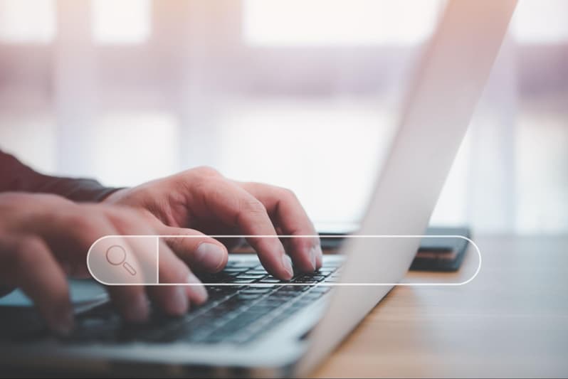 hands typing on a laptop with a search box overlay