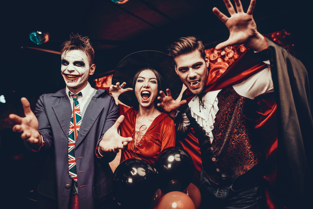 Young happy people in costumes celebrating Halloween